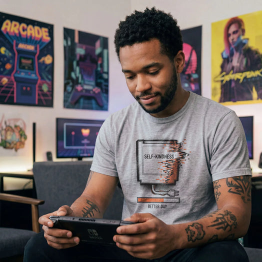 Sports grey tee with a retro gaming cartridge labeled Self-Kindness glitching above a Better Day orange loading bar.