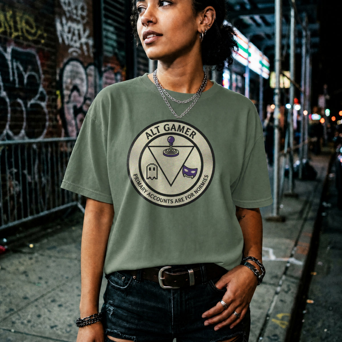 Translation missing: en.Military green t-shirt with a retro arcade badge reading Alt Gamer Primary Accounts Are For Normies with purple joystick