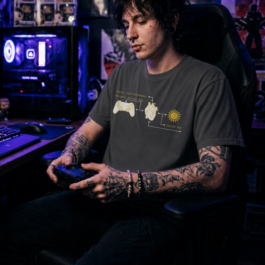 Translation missing: en.Charcoal tee with gold flowchart connecting a game controller, anatomical heart, sun, and text Input self-kindness