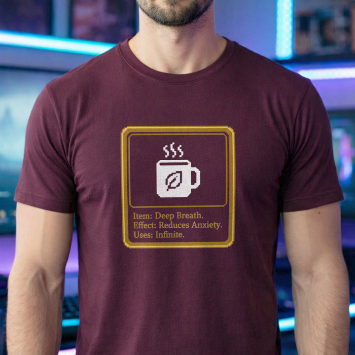 Translation missing: en.Maroon shirt with a pixel art mug inside a gold box reading Item: Deep Breath, Effect: Reduces Anxiety, Uses: Infinite