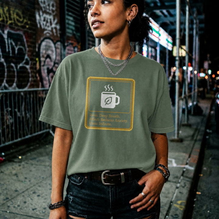 Translation missing: en.Military green shirt with a pixel art mug inside a gold box reading Item: Deep Breath, Effect: Reduces Anxiety, Uses: Infinite