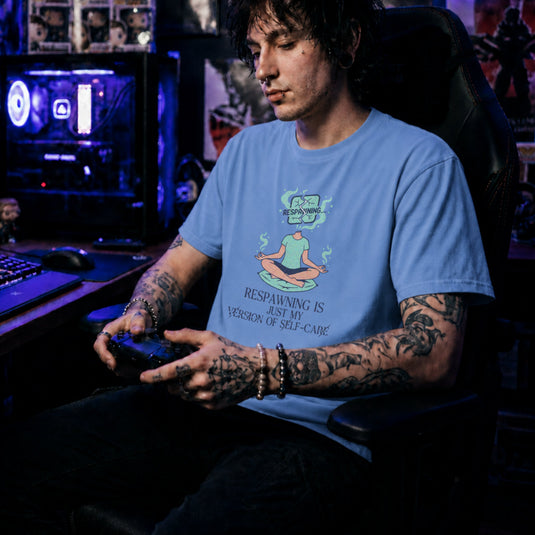 Translation missing: en.Carolina blue gamer tee with a meditating person graphic and text Respawning is just my version of self-care