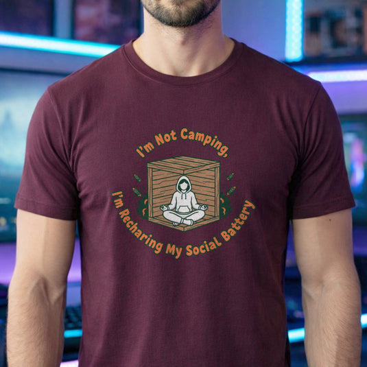 Translation missing: en.Maroon gamer tee graphic with text I'm Not Camping, I'm Recharging My Social Battery and person in a wooden box