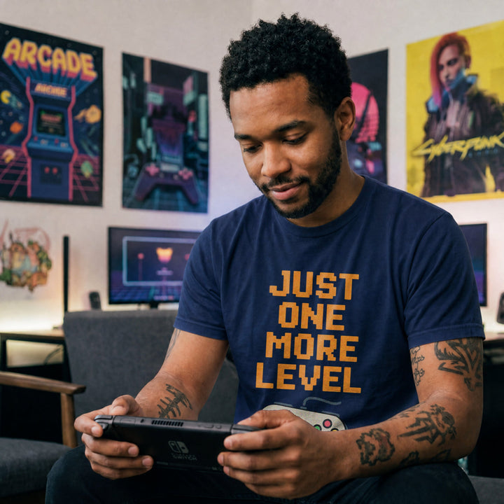 Translation missing: en.Retro navy t-shirt with orange pixelated text reading Just One More Level above a classic retro game controller