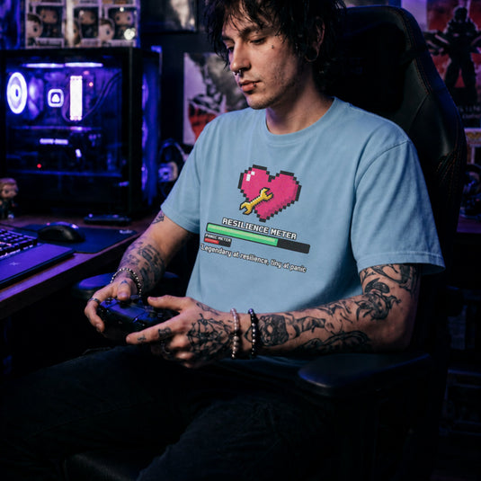 Translation missing: en.Light blue gamer tee graphic with pixel heart, wrench, loading bar, and text Legendary at resilience, tiny at panic
