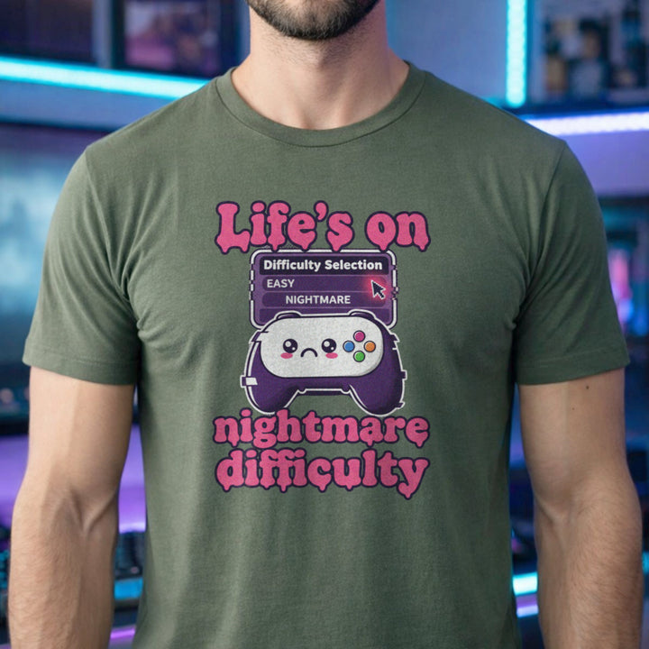 Translation missing: en.Military green tee with pink text reading Life's on nightmare difficulty next to a sad controller and difficulty selector