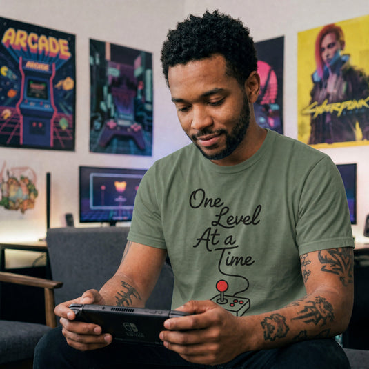 Translation missing: en.Military green cotton tee with retro arcade joystick graphic and text "One Level At A Time"
