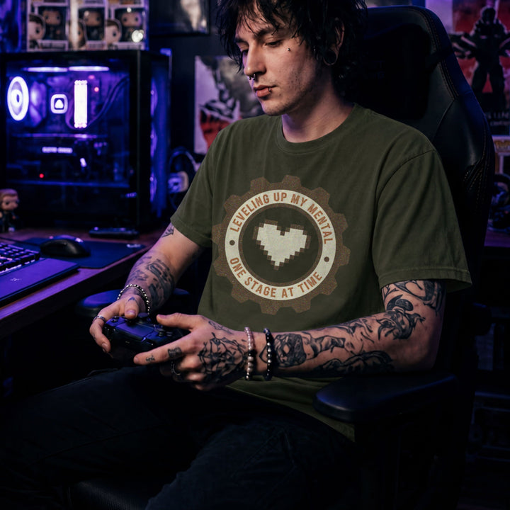 Translation missing: en.Military Green tee with pixel heart centered in cog badge graphic text, "leveling up my mental one stage at a time"