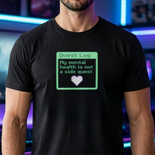 Translation missing: en.Black shirt with a green pixel art quest log graphic reading My mental health is not a side quest with a heart