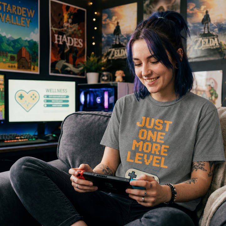 Translation missing: en.Retro graphite heather t-shirt with orange pixelated text reading Just One More Level above a classic retro game controller