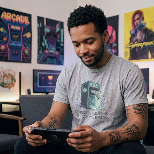 Translation missing: en.Sports grey tee with a meditating figure holding a cracked head by a Save Station. Text: Saving the game and my sanity