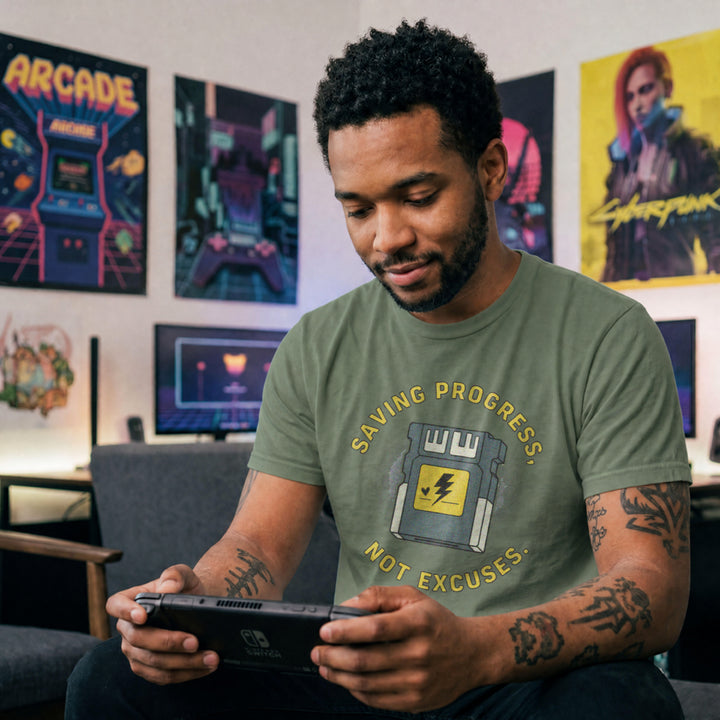 Translation missing: en.Military green t-shirt with yellow text reading Saving Progress, Not Excuses around a retro console memory card icon