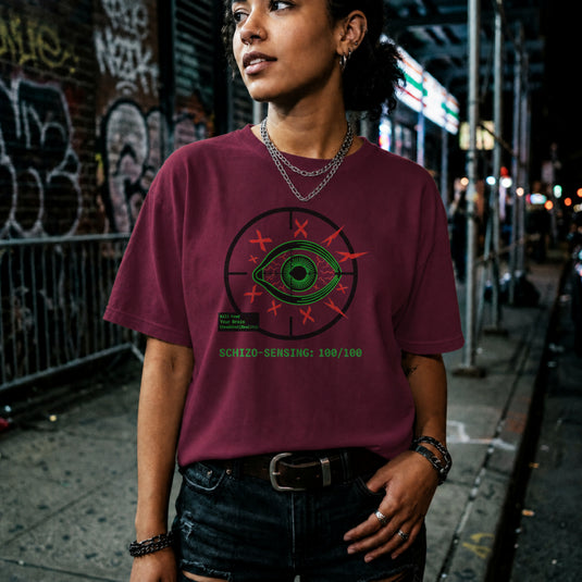 Translation missing: en.Green eye in a crosshair target with red Xs, a green kill feed text box, and Schizo Sensing on a maroon tee shirt