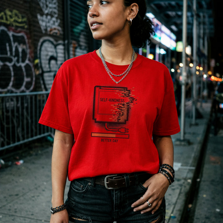 Translation missing: en.Red tee with a retro gaming cartridge labeled Self-Kindness glitching above a Better Day orange loading bar