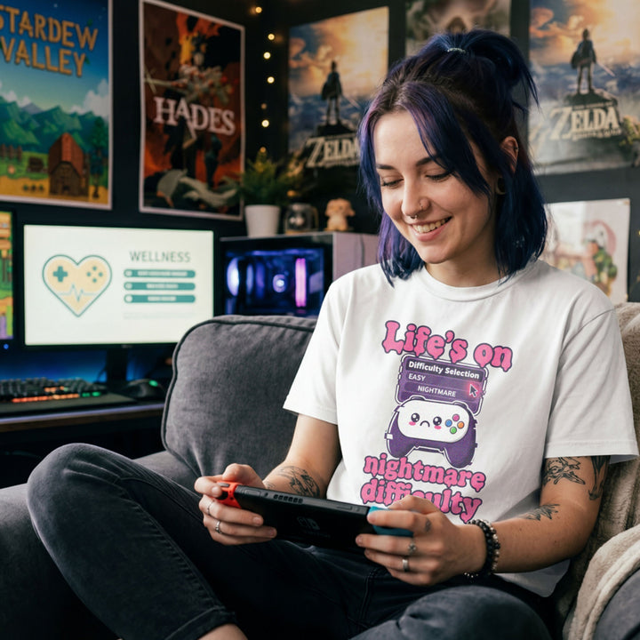 Translation missing: en.White tee with pink text reading Life's on nightmare difficulty next to a sad controller and difficulty selector