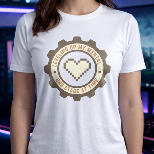 Translation missing: en.White tee with pixel heart centered in cog badge graphic text, "leveling up my mental one stage at a time"