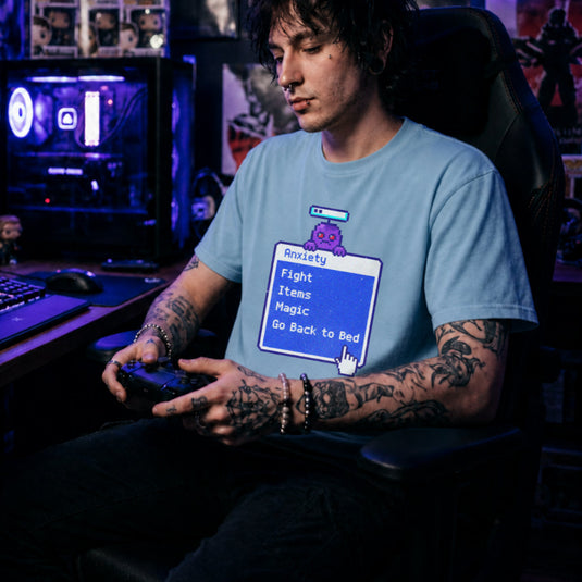 Translation missing: en.Alt n Vibe light blue t-shirt featuring a retro blue RPG battle menu box titled Anxiety with option Go Back to Bed