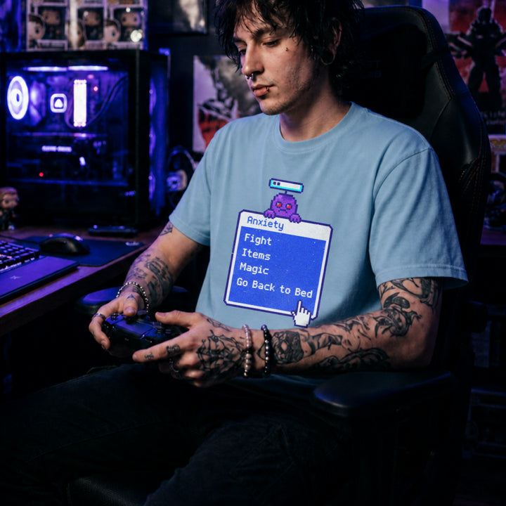 Translation missing: en.Light blue t-shirt featuring a retro blue RPG battle menu box titled Anxiety with option Go Back to Bed