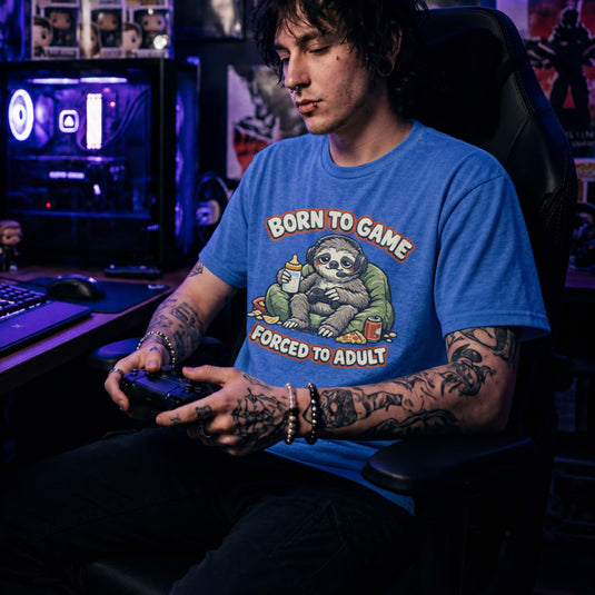 Translation missing: en.Heather royal t-shirt featuring a cute sloth gamer graphic with text Born to Game Forced to Adult in orange text