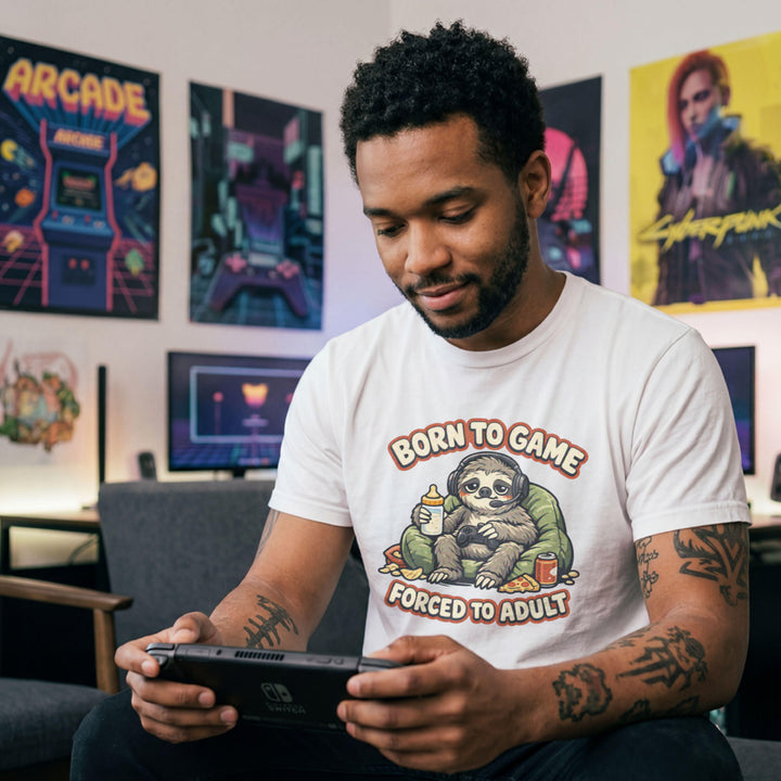 Translation missing: en.White t-shirt featuring a cute sloth gamer graphic with text Born to Game Forced to Adult in orange text