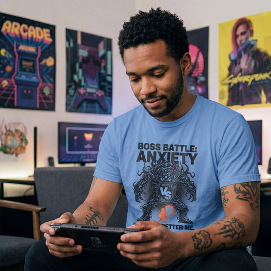 Translation missing: en.Carolina blue t-shirt with a black line-art monster graphic reading Boss Battle: Anxiety vs a player with a orange shield