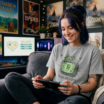 Translation missing: en.Sports grey t-shirt with a green retro TV displaying a large ear graphic and text reading THE GAME AUDIO IS LEAKING