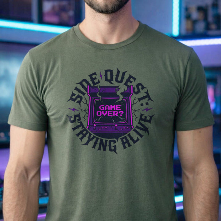 Translation missing: en.Military green t-shirt with cracked purple arcade cabinet, smoke, and text: Side Quest: Staying Alive, Game Over? graphic