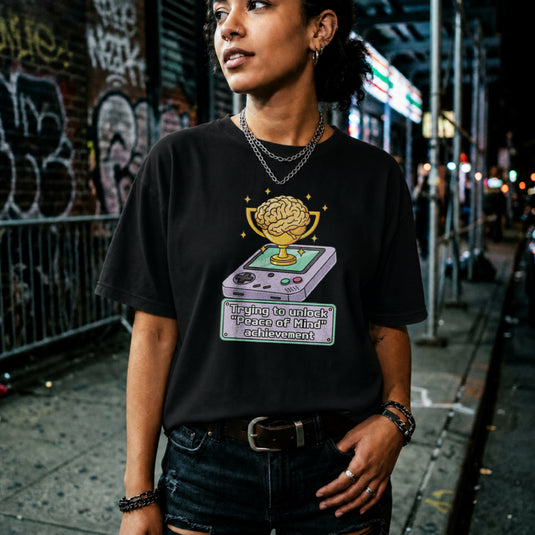 Translation missing: en.Black t-shirt featuring a retro handheld console with a brain trophy and Peace of Mind achievement text box