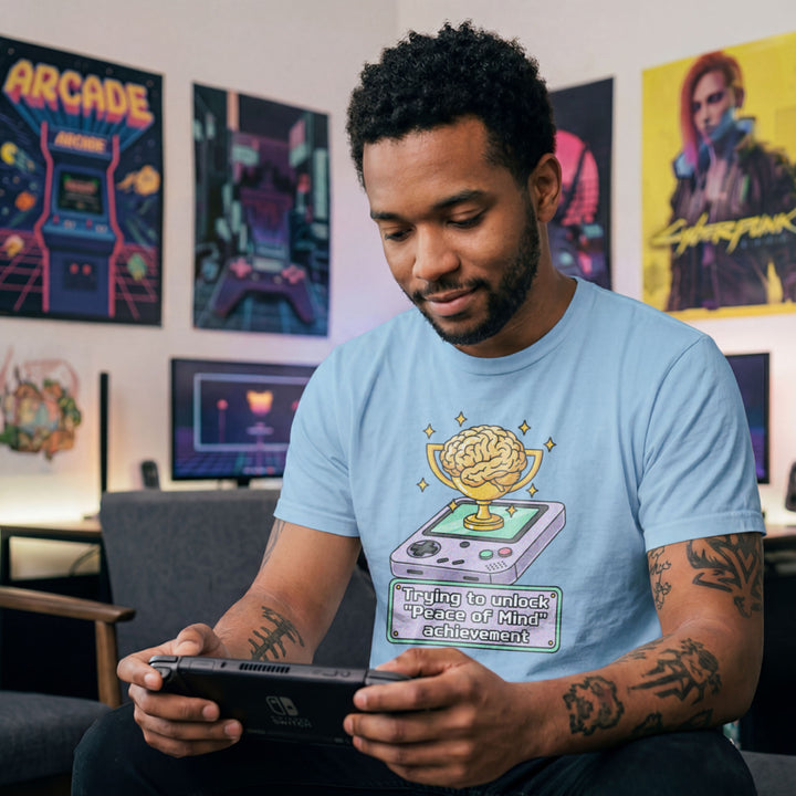 Translation missing: en.Light blue t-shirt featuring a retro handheld console with a brain trophy and Peace of Mind achievement text box