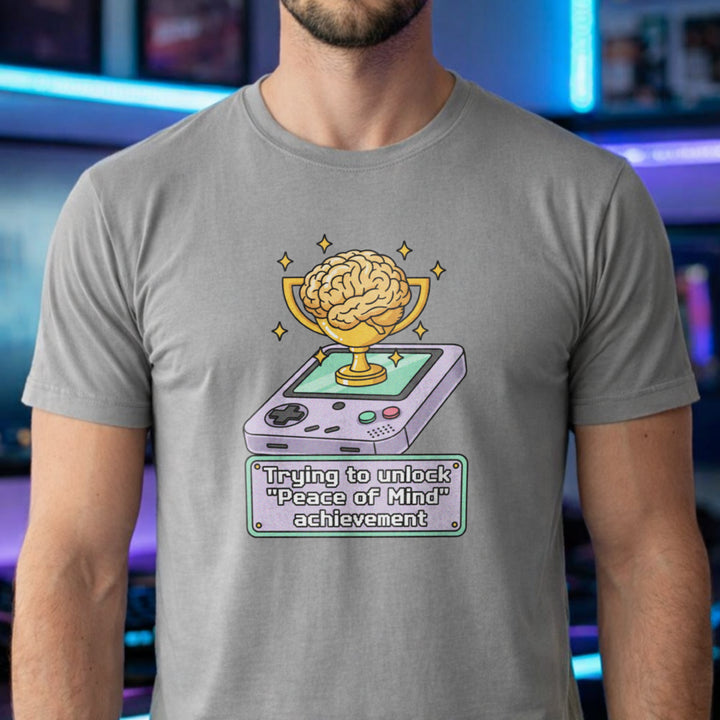 Translation missing: en.Sports grey t-shirt featuring a retro handheld console with a brain trophy and Peace of Mind achievement text box