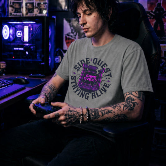Translation missing: en.Sports grey t-shirt with cracked purple arcade cabinet, smoke, and text: Side Quest: Staying Alive, Game Over? graphic