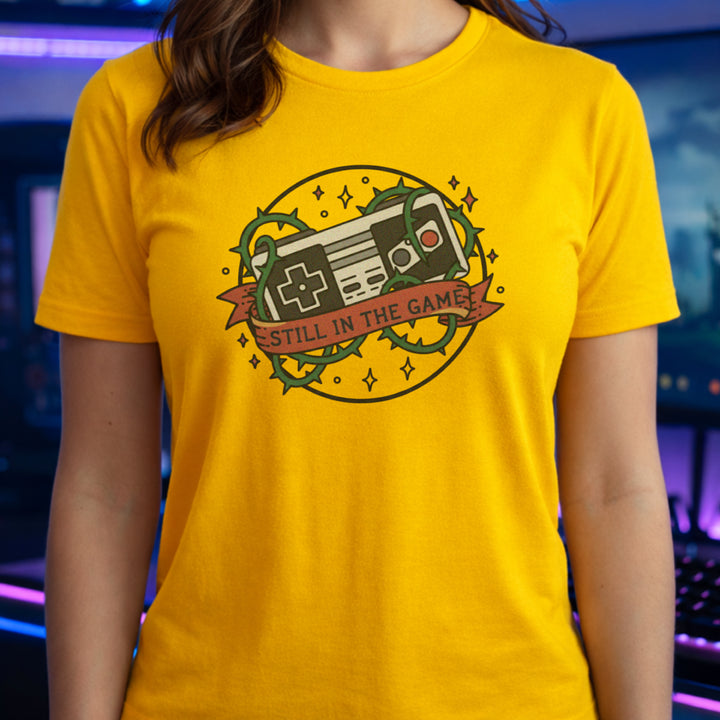 Translation missing: en.Daisy t-shirt with a classic retro controller tangled in green thorns and a banner reading STILL IN THE GAME. 