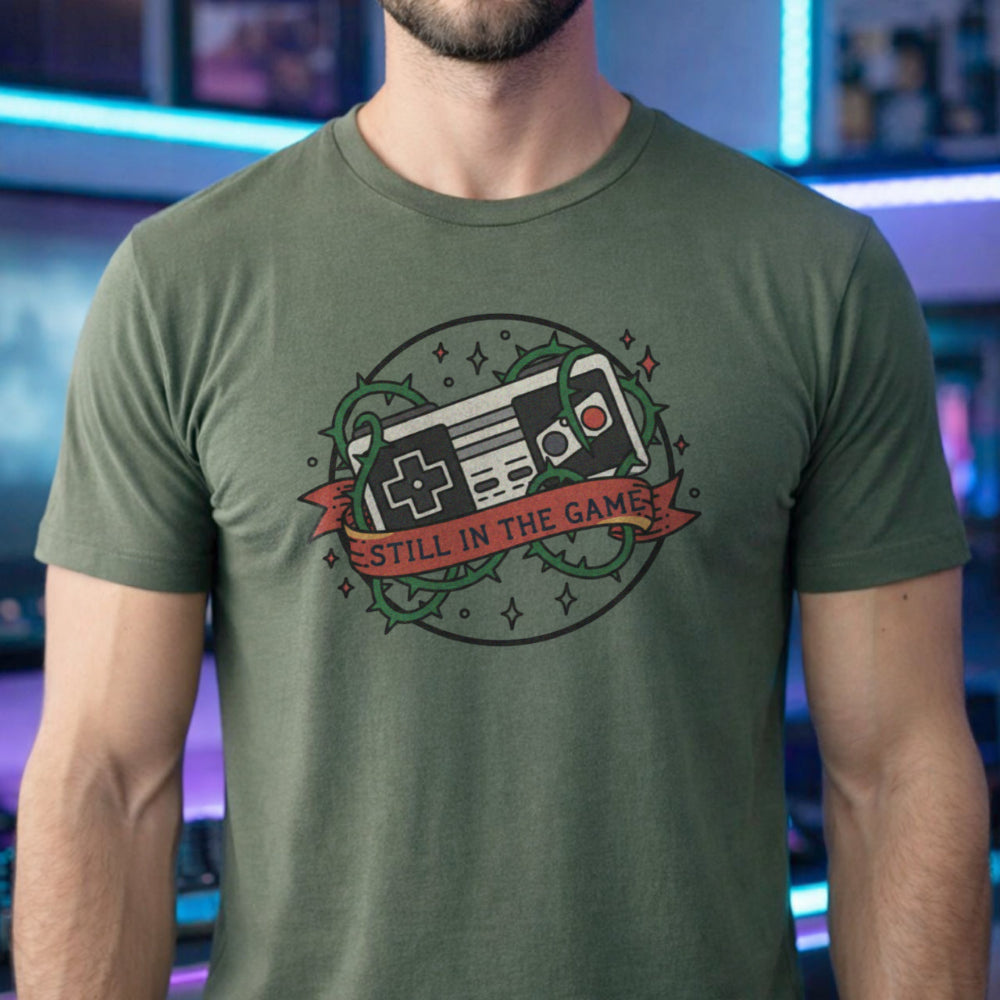 Translation missing: en.Alt n Vibe military green  t-shirt with a classic retro controller tangled in green thorns and a banner reading STILL IN THE GAME. 