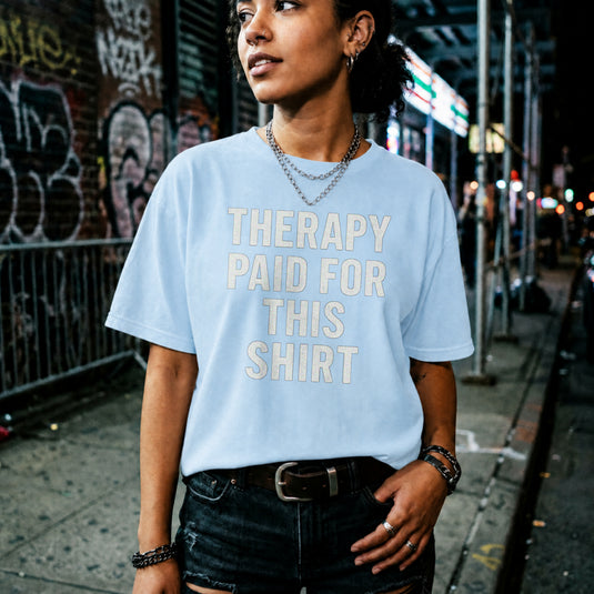 Translation missing: en.Light blue t-shirt printed with white bold text reading Therapy Paid For This Shirt